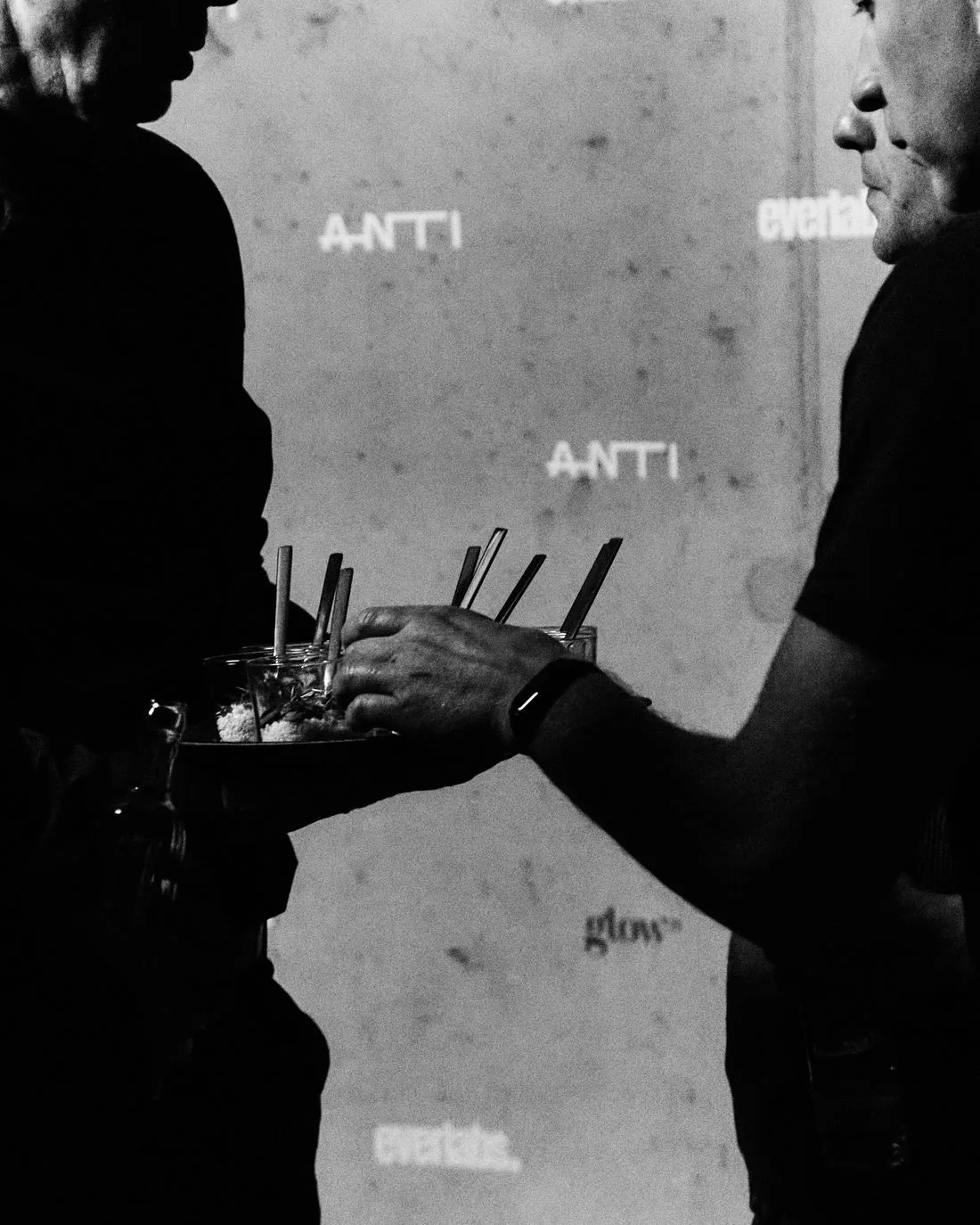 A tray of drinks carried past the ANTI backdrop at an event