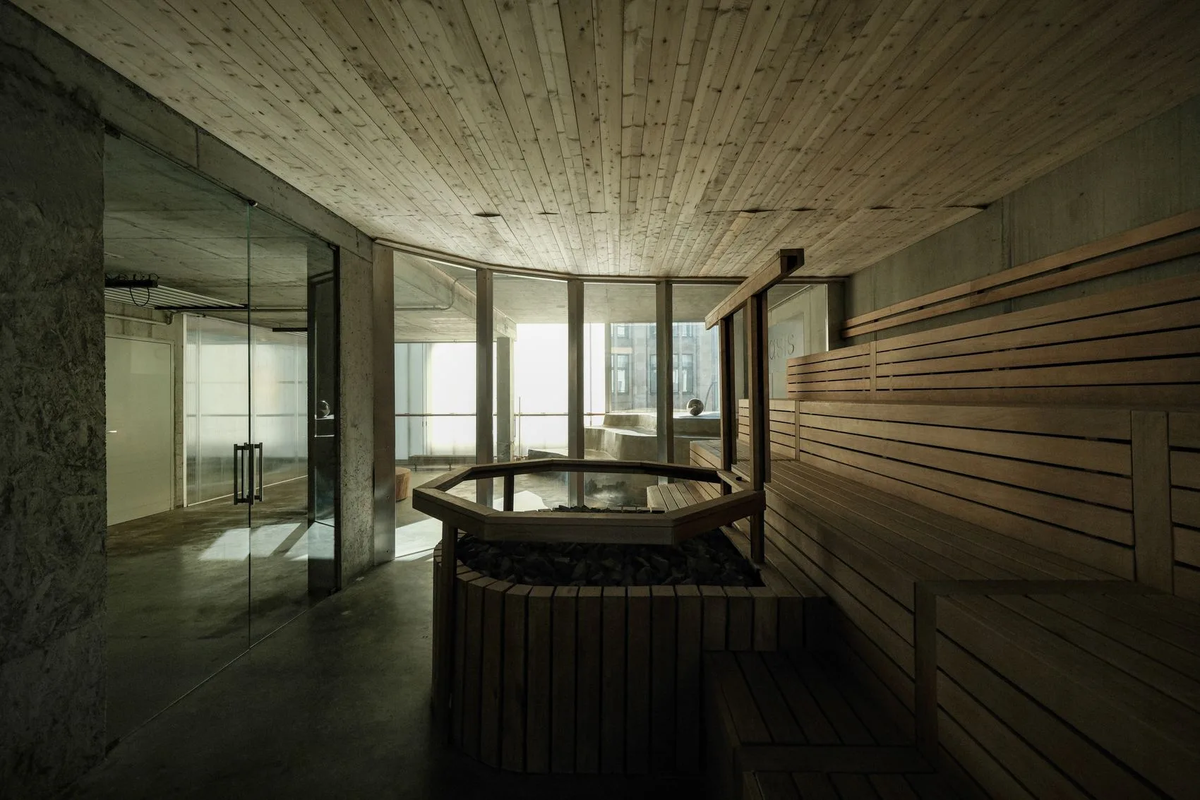 The ANTI sauna: blonde wood benches and ceiling around a stone-filled stove